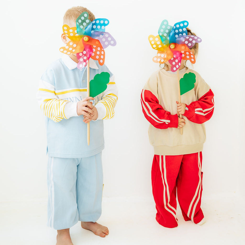 Two children holding colorful pinwheels against a white background