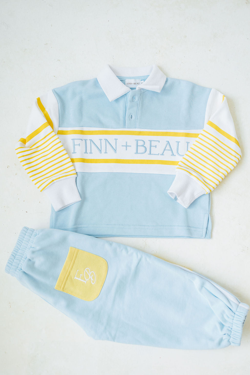 Children's light blue and yellow outfit with 'FINN + BEAU' branding on a white background