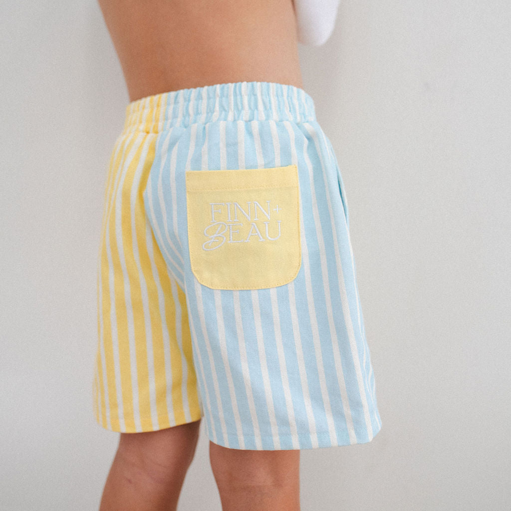 Person wearing yellow and blue striped shorts with a pocket on a plain background