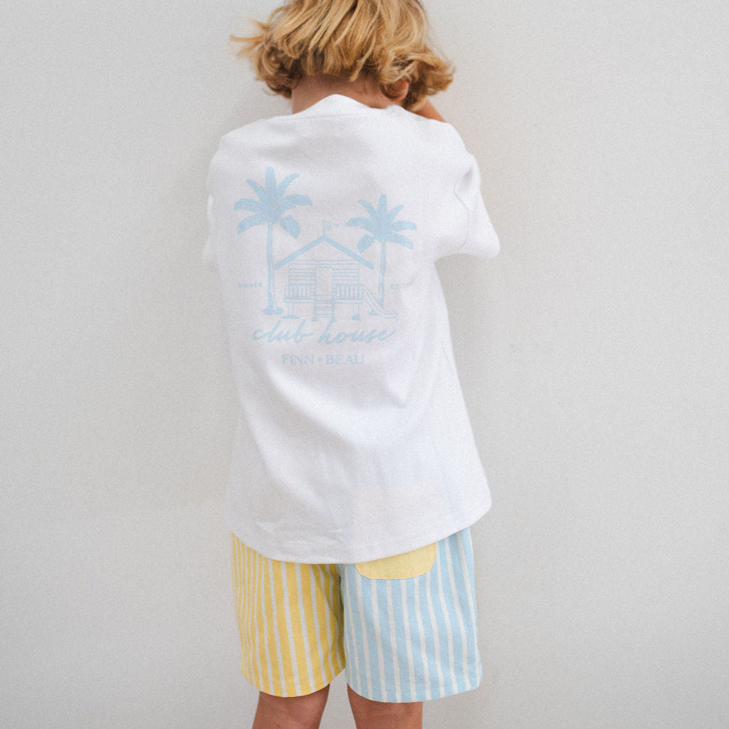 Person wearing a white shirt with a blue graphic and colorful shorts on a plain background