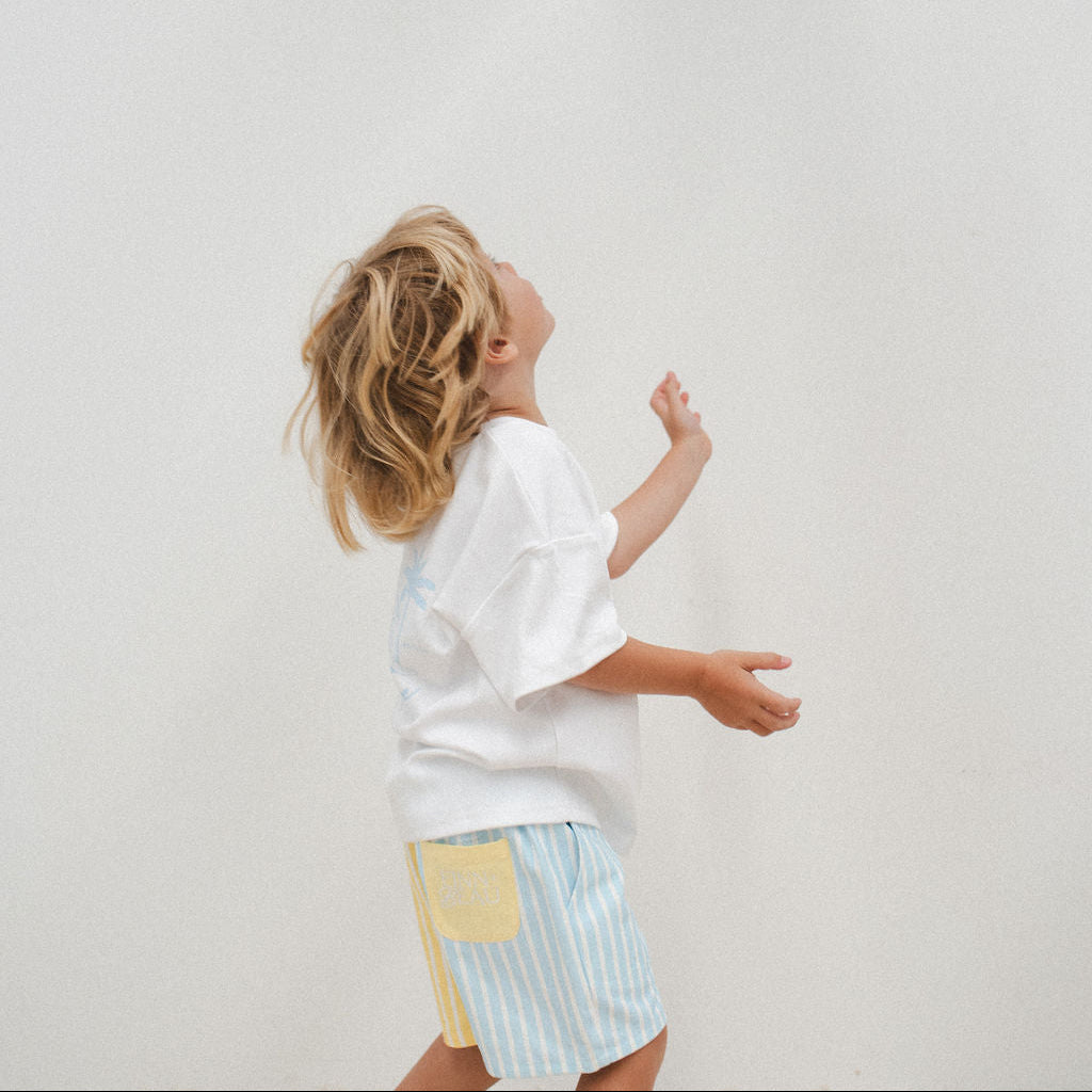 Person wearing a white shirt and colorful shorts against a plain background