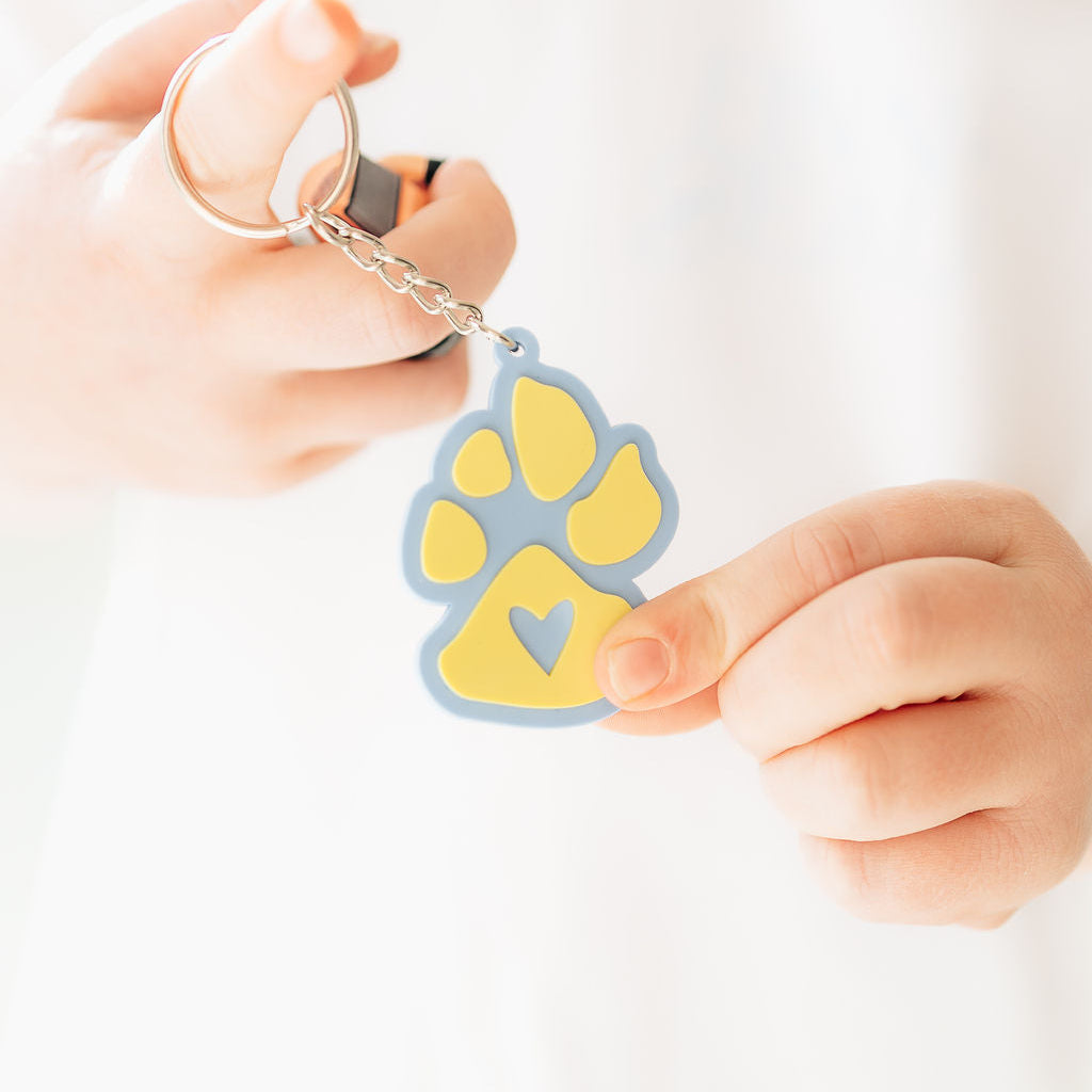 Person holding a keychain with a paw-shaped tag on a white background